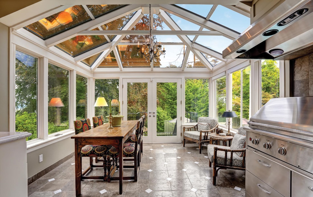 Four Seasons Conservatory Room with a Dining Room, Lounge Chairs, Stove, and Chandelier in It